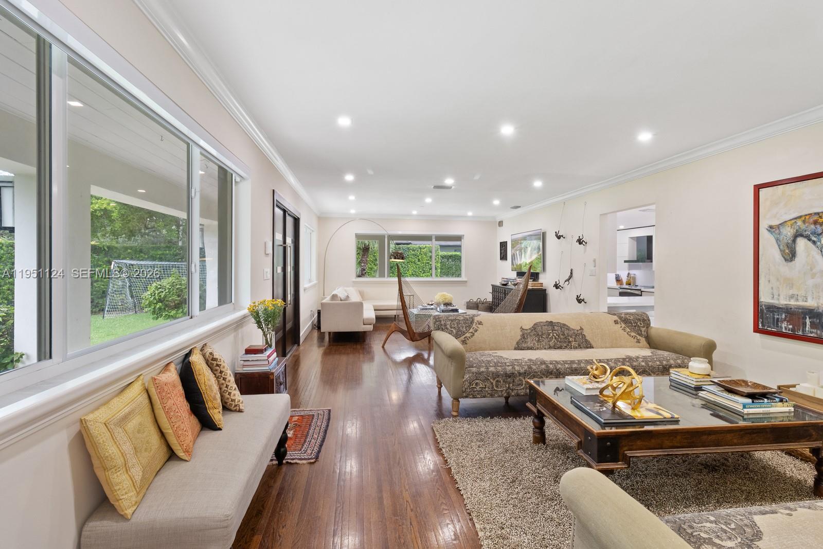 A living room features hardwood floors, a large window, and a patterned sofa — 5601 Maggiore St, Coral Gables FL 33146, CORAL GABLES, FL
