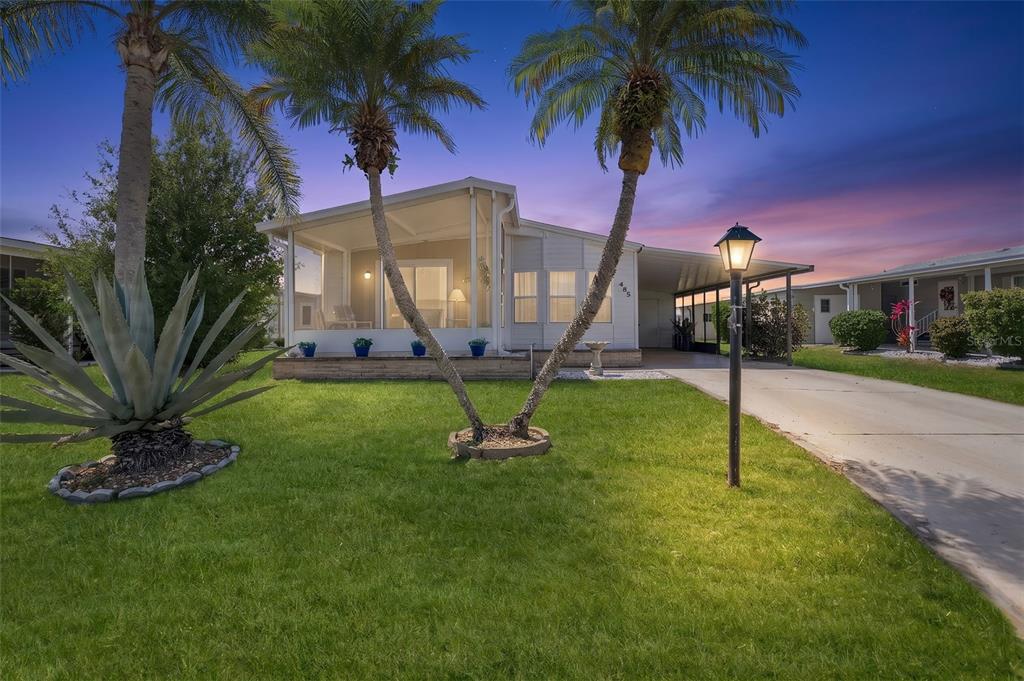 A single-story manufactured home with a screened porch, palm trees, and a concrete driveway — 485 LOMA LINDA, NORTH PORT, FL