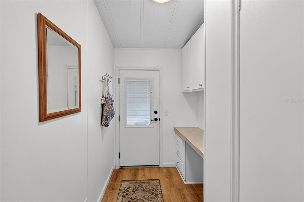 A laundry room or mudroom features white cabinets, a countertop, a mirror, and wood flooring — 485 LOMA LINDA, NORTH PORT, FL
