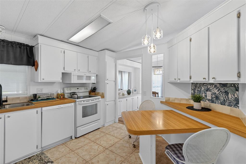 A kitchen features white cabinets, wood-look countertops, tile flooring, and a small dining table — 485 LOMA LINDA, NORTH PORT, FL