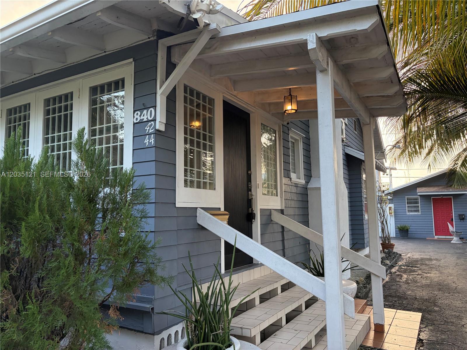 The exterior of a blue house features a covered porch, white railings, and tiled steps — 840 SW 13th Ave, Miami FL 33135, MIAMI, FL