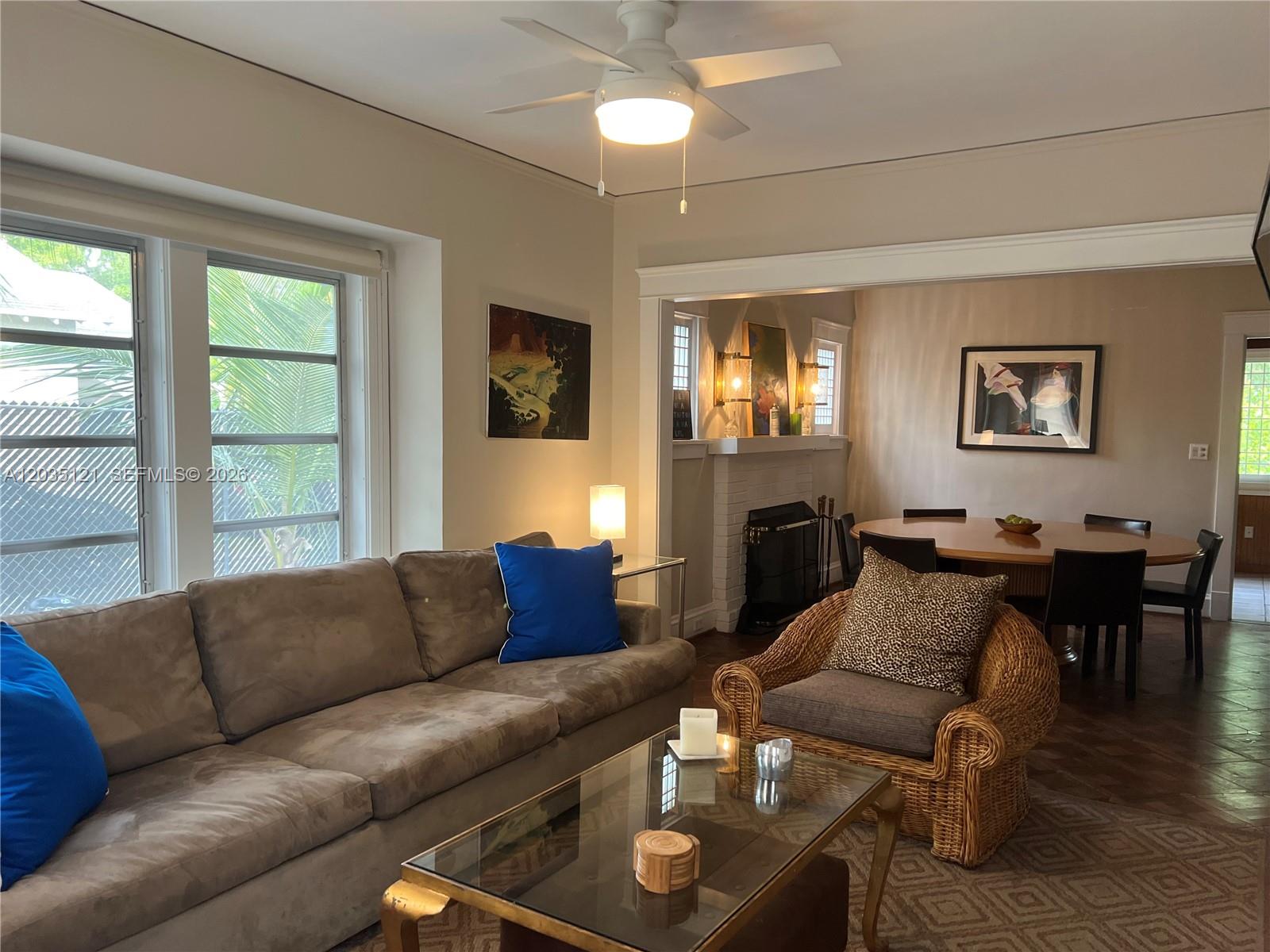 A living room with a brown sofa, wicker chair, glass coffee table, and adjacent dining area — 840 SW 13th Ave, Miami FL 33135, MIAMI, FL