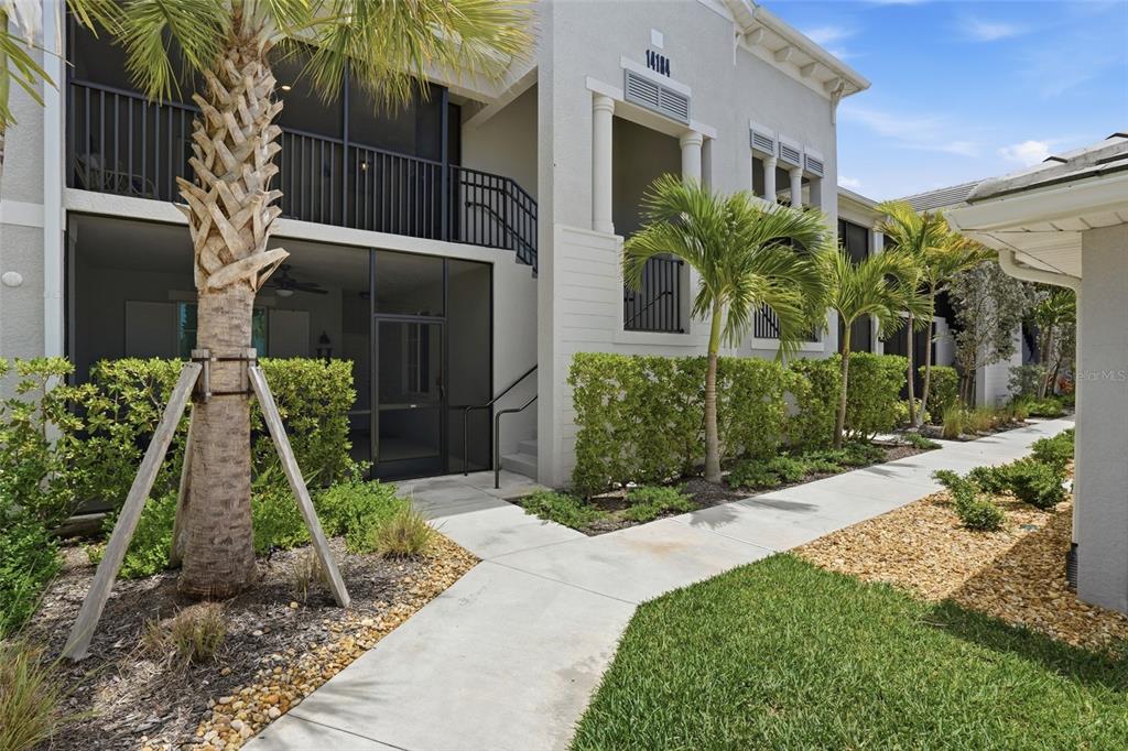 A two-story apartment building exterior features a screened-in patio, a palm tree, and a walkway — 14184 HERITAGE LANDING BOULEVARD UNIT 525, PUNTA GORDA, FL