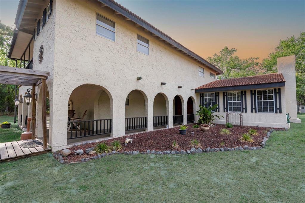 A two-story stucco house features a covered arched porch and a landscaped garden bed — 12311 OAKWOOD DRIVE, HUDSON, FL
