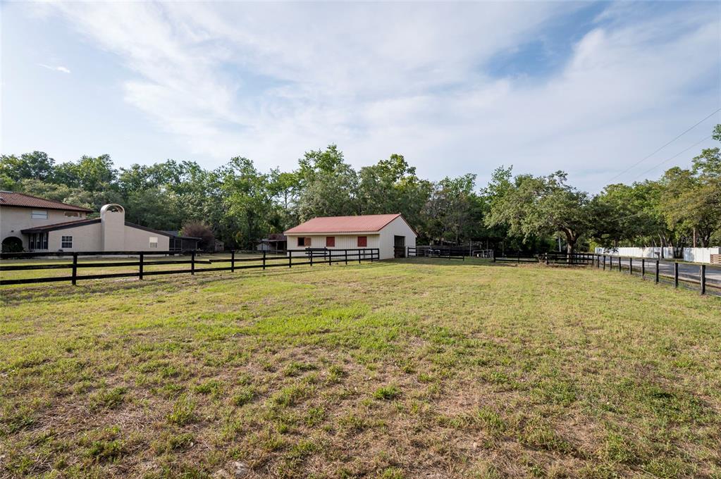 A grassy pasture features a fenced-in area with a barn and a house nearby — 12311 OAKWOOD DRIVE, HUDSON, FL