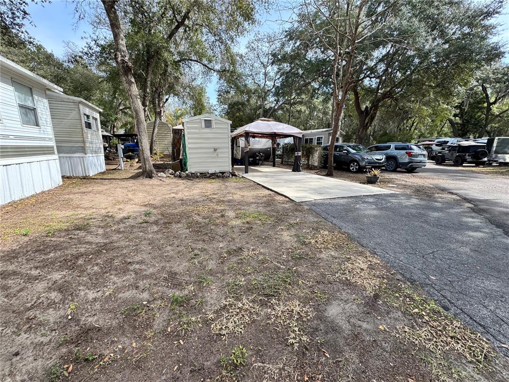A gravel and dirt yard features a small shed, a gazebo, and parked vehicles — 25325 NE 141ST STREET, SALT SPRINGS, FL