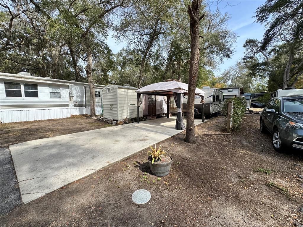 A concrete driveway leads to a gazebo, a storage shed, and a parked travel trailer — 25325 NE 141ST STREET, SALT SPRINGS, FL