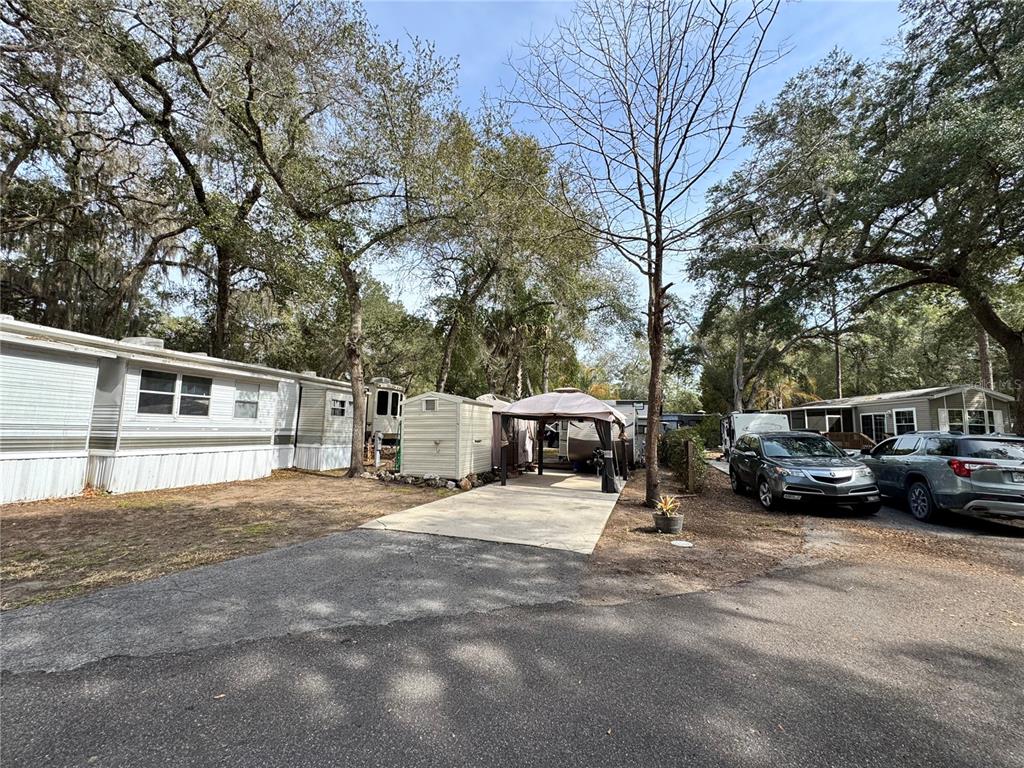 A paved driveway leads to a small shed and a covered patio area between mobile homes — 25325 NE 141ST STREET, SALT SPRINGS, FL