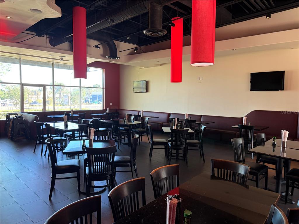 A restaurant dining room features dark wood tables, black chairs, and tall red pendant lights — TBA SW ARCHER ROAD UNIT D, GAINESVILLE, FL