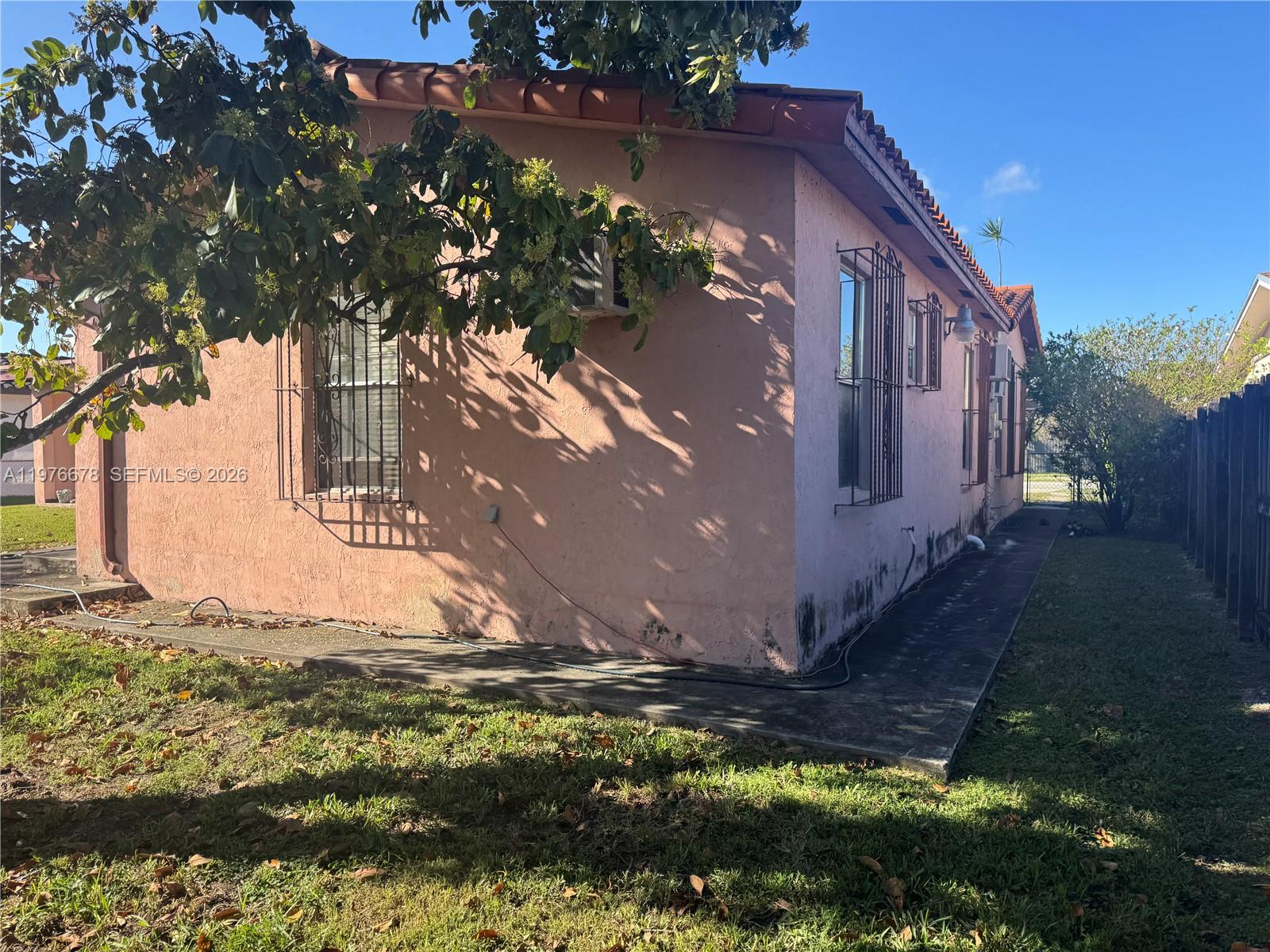 The exterior of a pink stucco house features a tiled roof and barred windows — 10730 SW 66th Dr, Miami FL 33173, MIAMI, FL