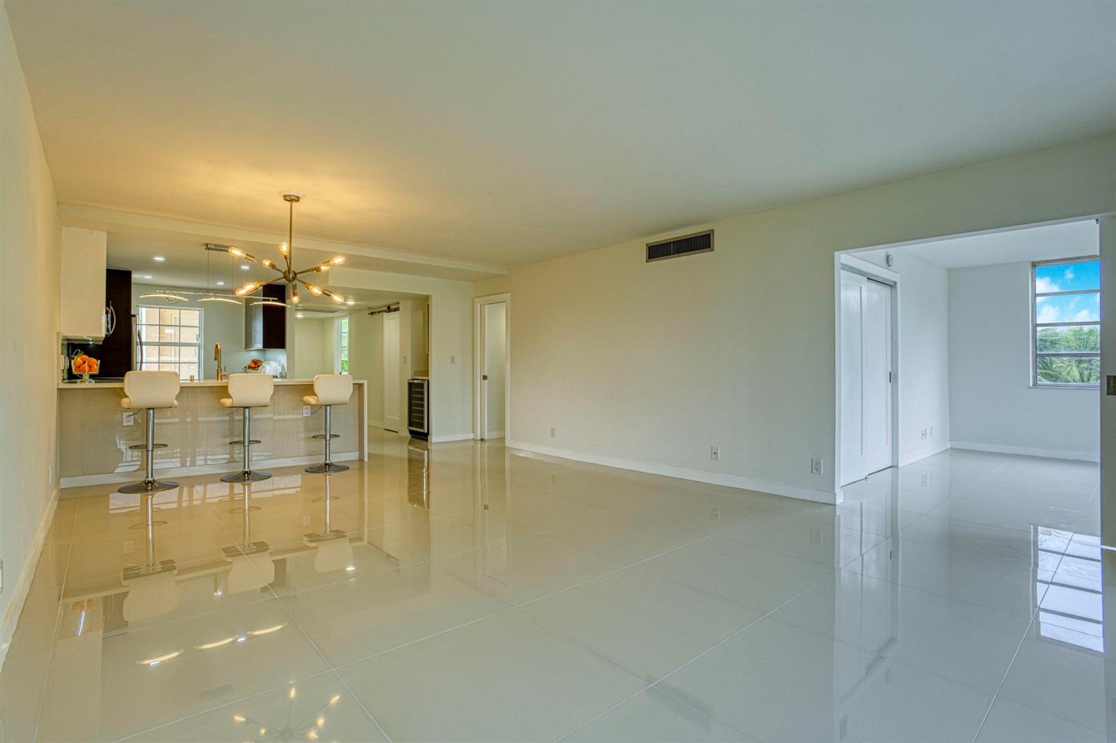An open-concept living area features white tile flooring, a kitchen breakfast bar, and recessed lighting — 535 Oaks Drive # 510, Pompano Beach FL 33069, POMPANO BEACH, FL