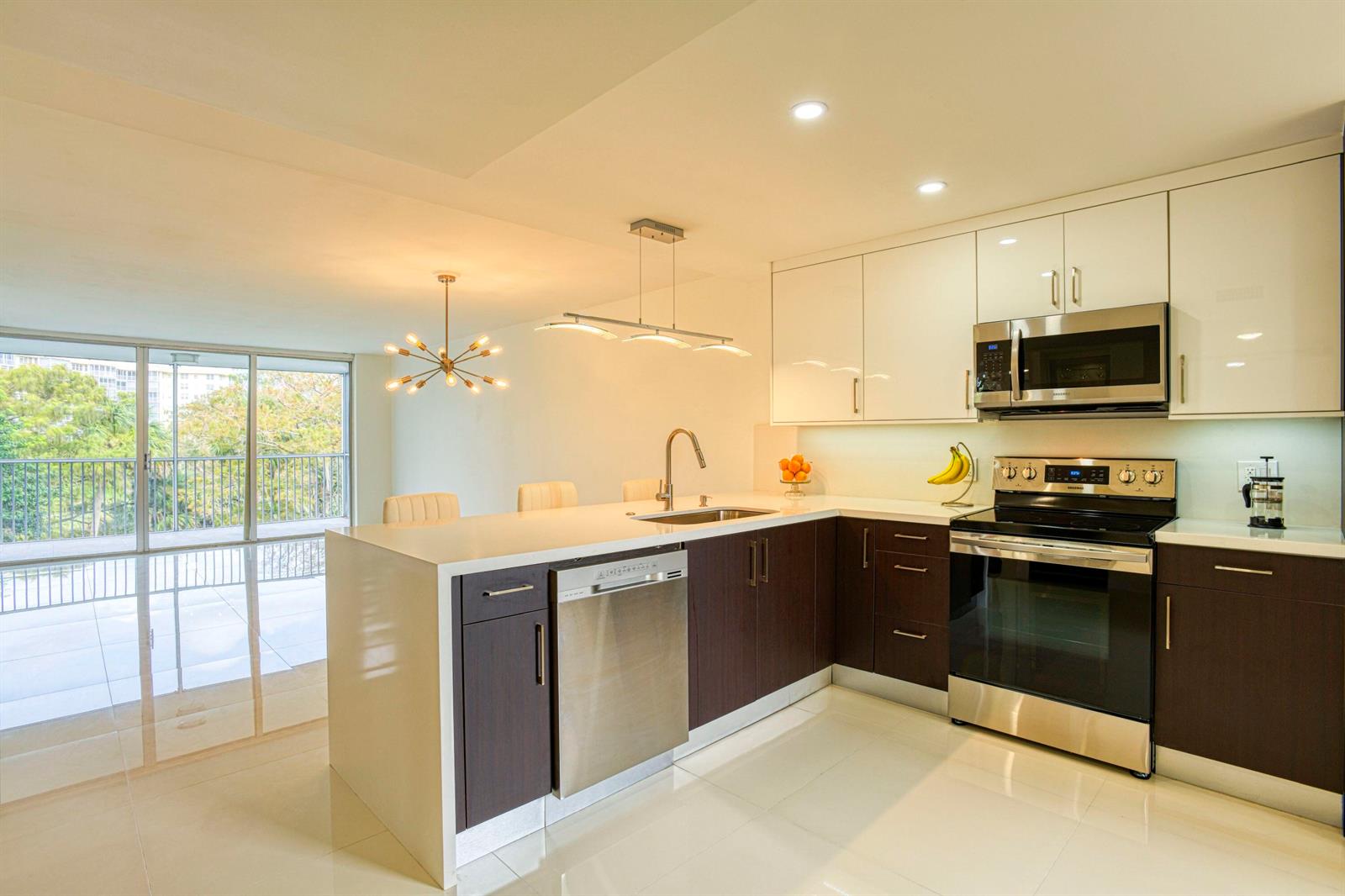 A modern kitchen features dark wood lower cabinets, white upper cabinets, and a breakfast bar island — 535 Oaks Drive # 510, Pompano Beach FL 33069, POMPANO BEACH, FL