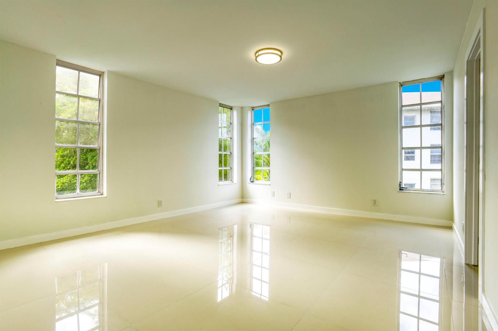 An empty room with glossy tile floors, white walls, and multiple windows — 535 Oaks Drive # 510, Pompano Beach FL 33069, POMPANO BEACH, FL