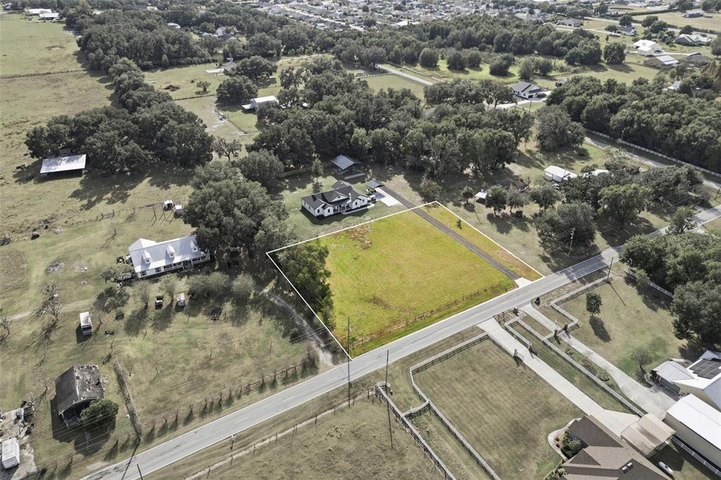 An aerial view shows a vacant, rectangular grassy lot outlined in white next to a road — SOCRUM LOOP ROAD W, LAKELAND, FL