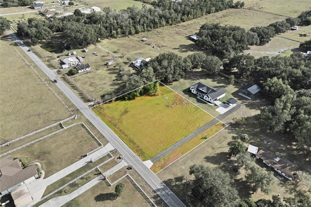 An aerial view shows a vacant rectangular lot outlined in white next to a house — SOCRUM LOOP ROAD W, LAKELAND, FL