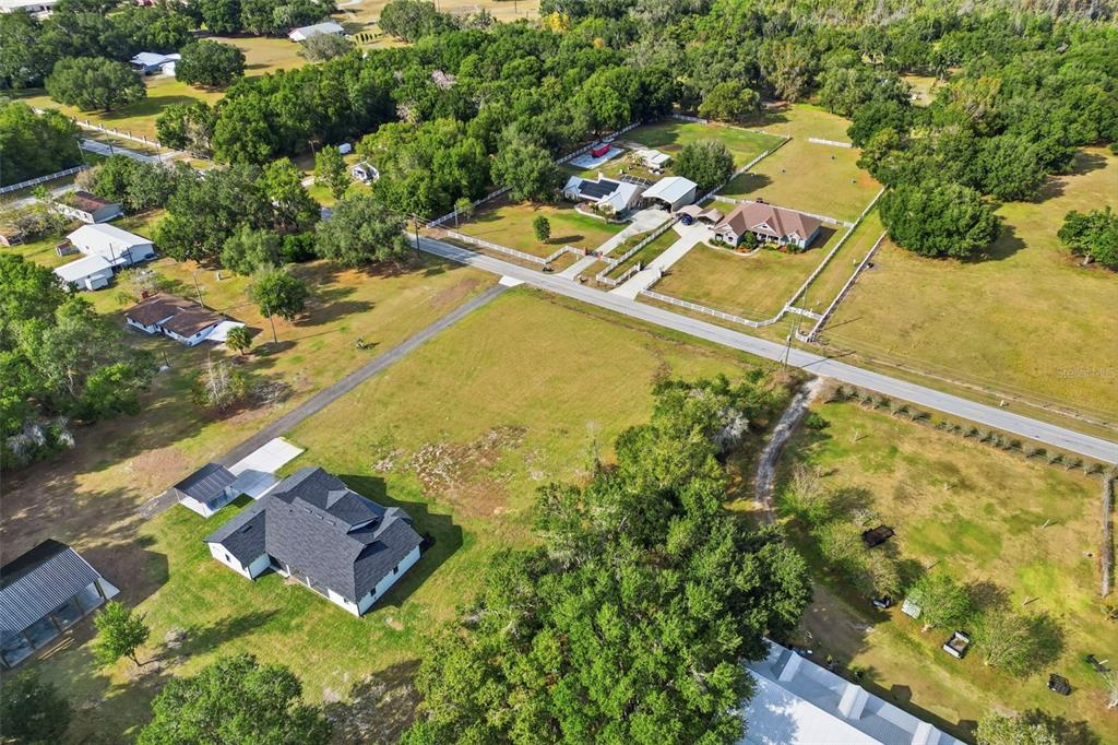 An aerial view shows several houses with fenced yards surrounded by trees and open fields — SOCRUM LOOP ROAD W, LAKELAND, FL