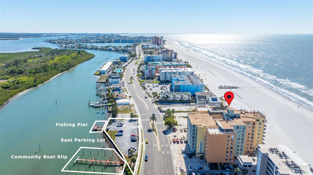 An aerial view shows a coastal building, a parking lot, a fishing pier, and boat slips — 18610 GULF BOULEVARD UNIT 709, INDIAN SHORES, FL