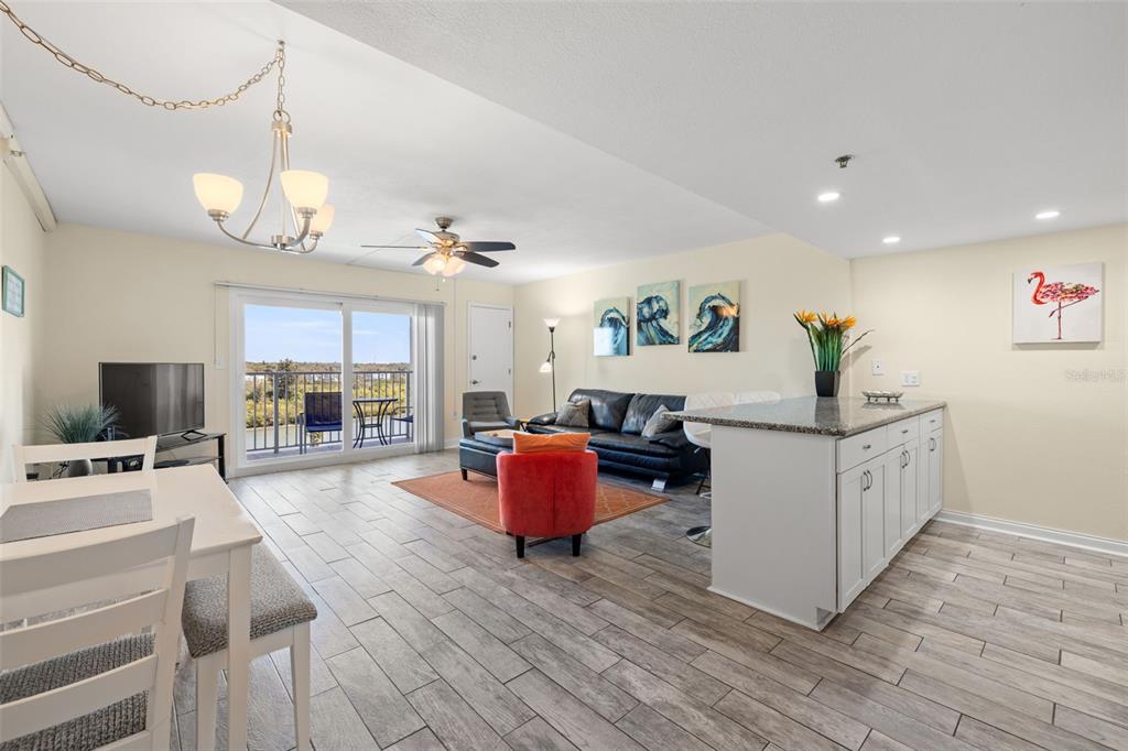 An open-concept living and dining area features tile flooring, a kitchen island, and balcony access — 18610 GULF BOULEVARD UNIT 709, INDIAN SHORES, FL