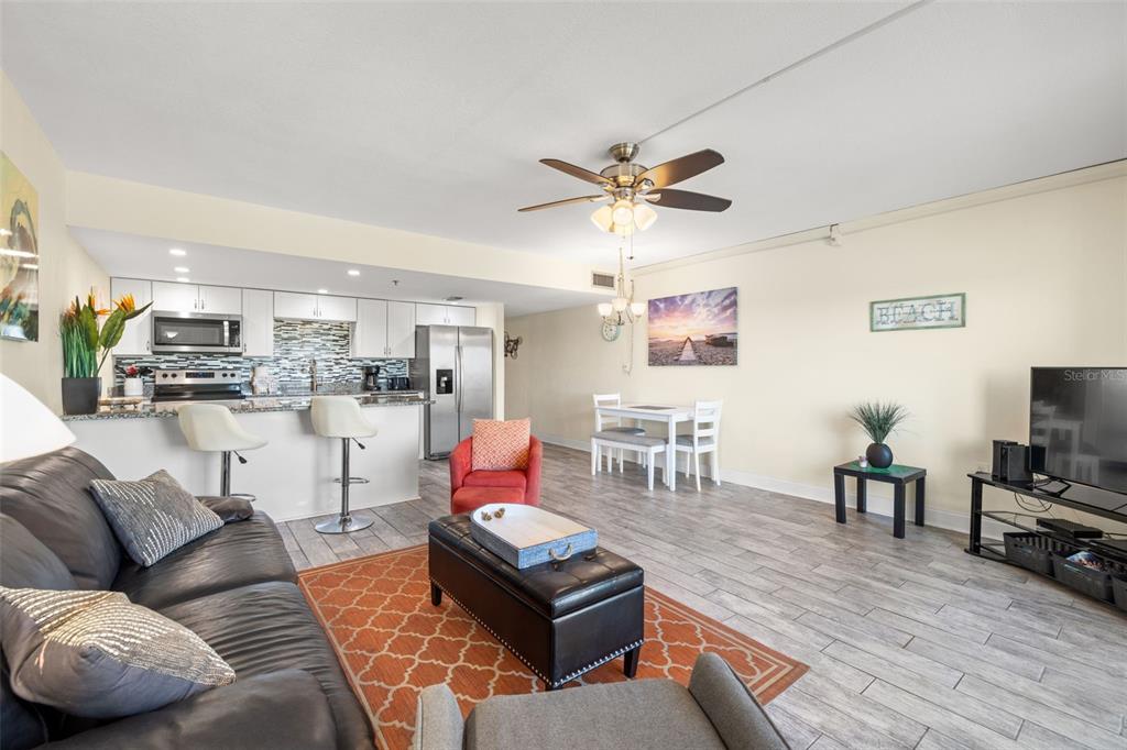 An open-concept living room and kitchen featuring tile floors, white cabinetry, and a breakfast bar — 18610 GULF BOULEVARD UNIT 709, INDIAN SHORES, FL