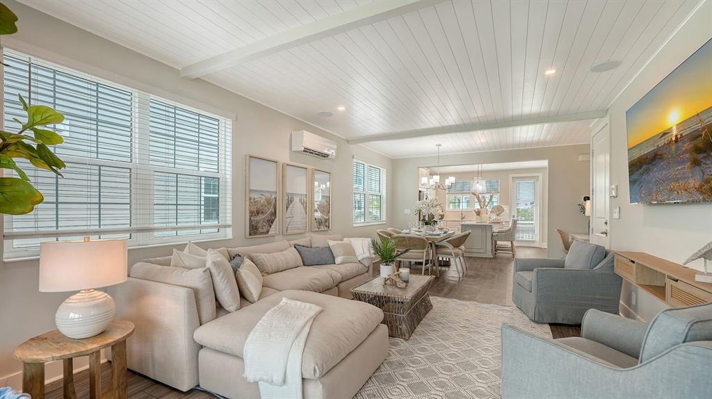An open-concept living and dining area features a sectional sofa, light wood floors, and shiplap ceilings — 12413 GULF BREEZE TERRACE, CORTEZ, FL