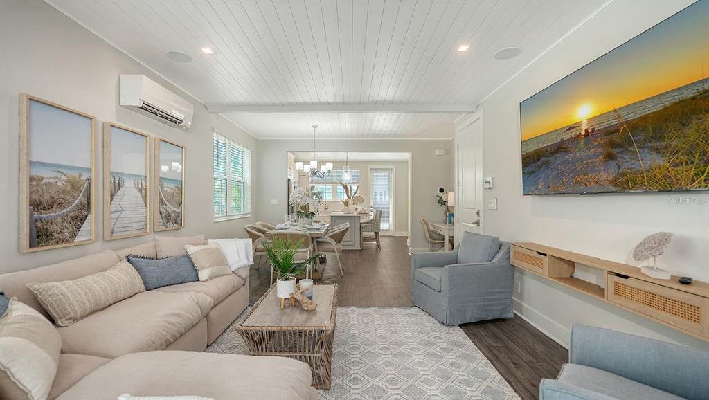 A living room features a sectional sofa, two armchairs, a wall-mounted television, and wood flooring — 12413 GULF BREEZE TERRACE, CORTEZ, FL