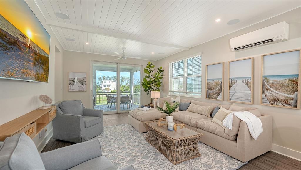 A living room features a sectional sofa, two armchairs, a television, and a balcony view — 12413 GULF BREEZE TERRACE, CORTEZ, FL