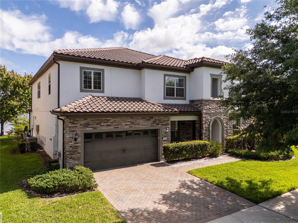 A two-story house with a stone facade, tile roof, and a brick paver driveway — 11142 LEMON LAKE BOULEVARD, ORLANDO, FL