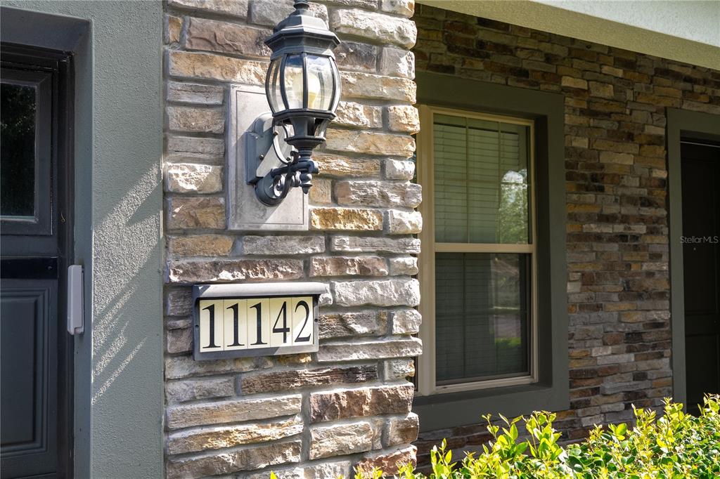 A stone-clad exterior wall features a house number plaque and a wall-mounted outdoor light — 11142 LEMON LAKE BOULEVARD, ORLANDO, FL