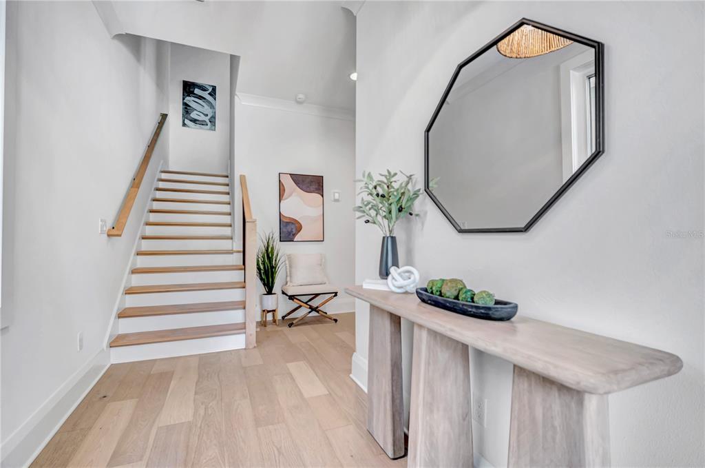 A bright entryway features light wood flooring, a staircase, a console table, and a wall mirror — 1524 S HABANA AVENUE, TAMPA, FL