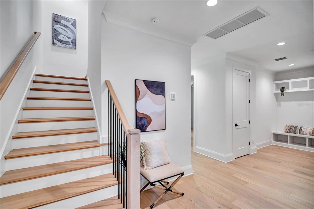 A staircase with wooden treads and black railings leads up next to a hallway — 1524 S HABANA AVENUE, TAMPA, FL