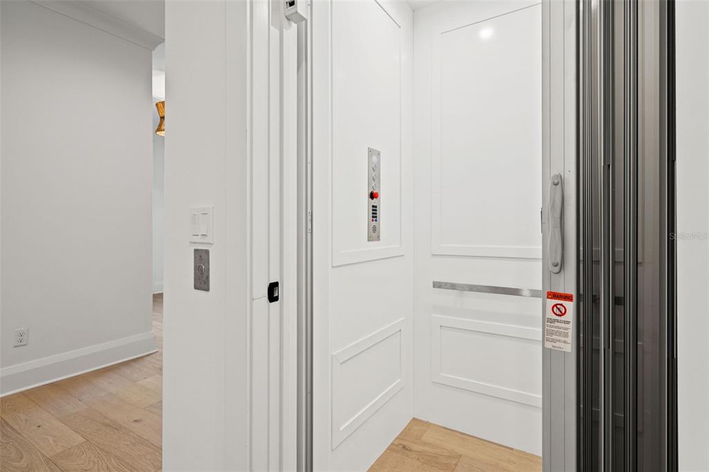 A residential elevator with white paneled walls and a metal accordion gate — 1524 S HABANA AVENUE, TAMPA, FL