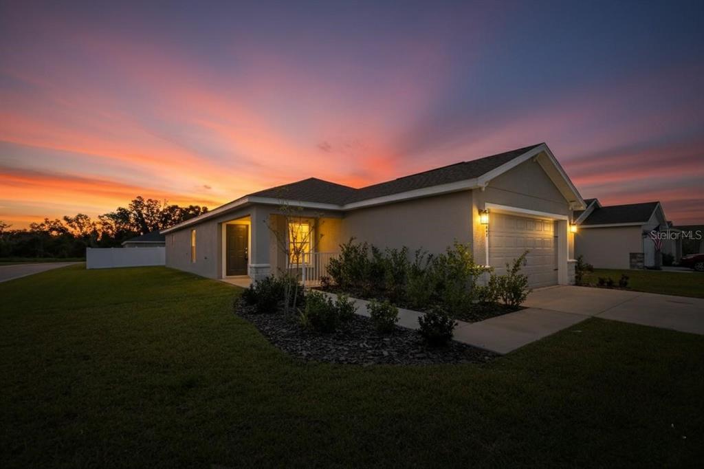 A single-story house with a garage and a landscaped yard under a sunset sky — 1047 ARUBA AVENUE, MULBERRY, FL
