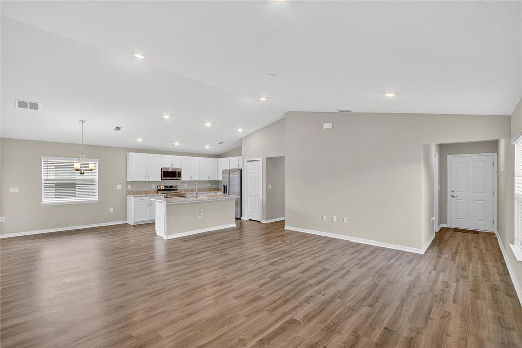 An open-concept kitchen and living area feature white cabinets, a center island, and wood flooring — 1047 ARUBA AVENUE, MULBERRY, FL