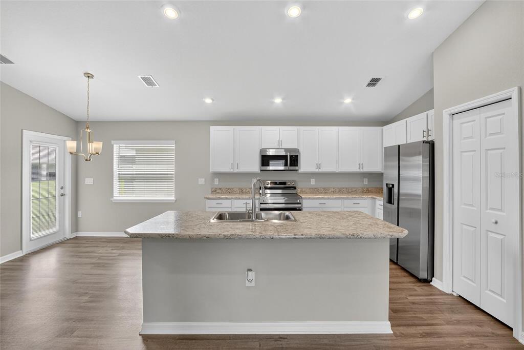 A kitchen features white cabinets, granite countertops, a center island, and stainless steel appliances — 1047 ARUBA AVENUE, MULBERRY, FL