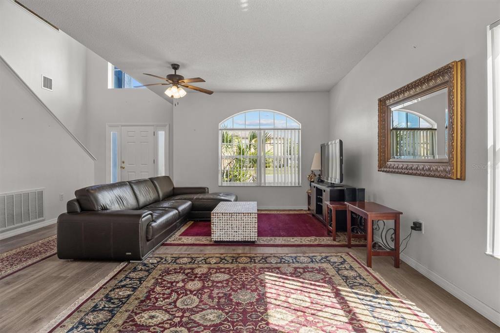 A living room features a brown leather sectional, a patterned rug, and a large mirror — 5500 WILLOW BEND TRAIL, KISSIMMEE, FL
