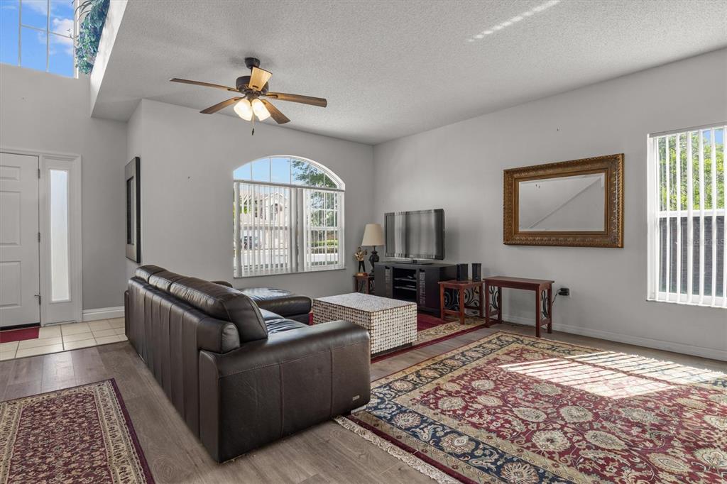 A living room features a dark leather sectional, a patterned area rug, and a ceiling fan — 5500 WILLOW BEND TRAIL, KISSIMMEE, FL