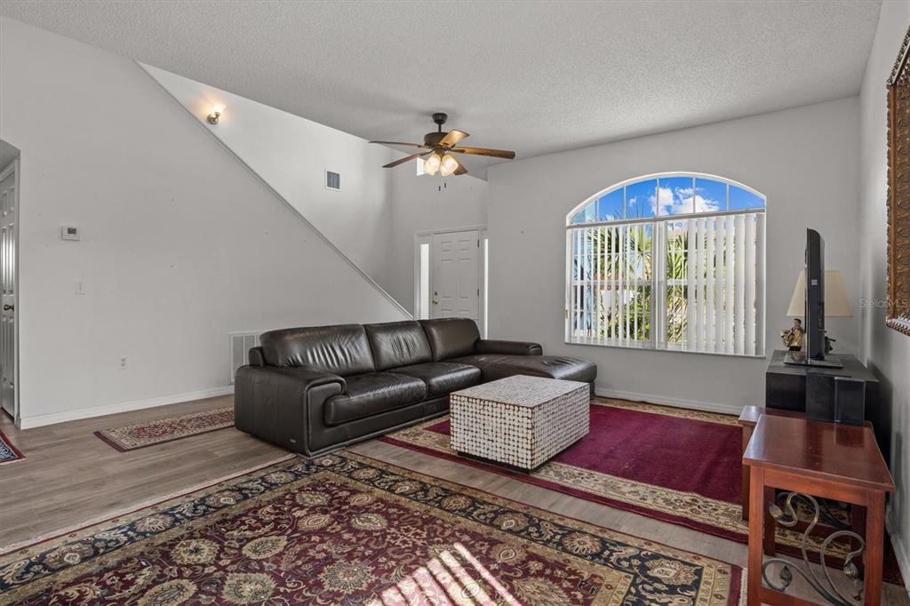 A living room with a dark leather sectional, a patterned rug, and a vaulted ceiling — 5500 WILLOW BEND TRAIL, KISSIMMEE, FL