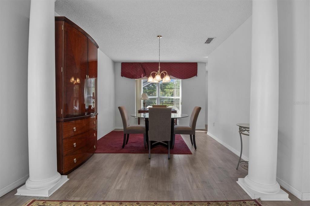 A dining room features a glass table, three chairs, a wooden cabinet, and two columns — 5500 WILLOW BEND TRAIL, KISSIMMEE, FL