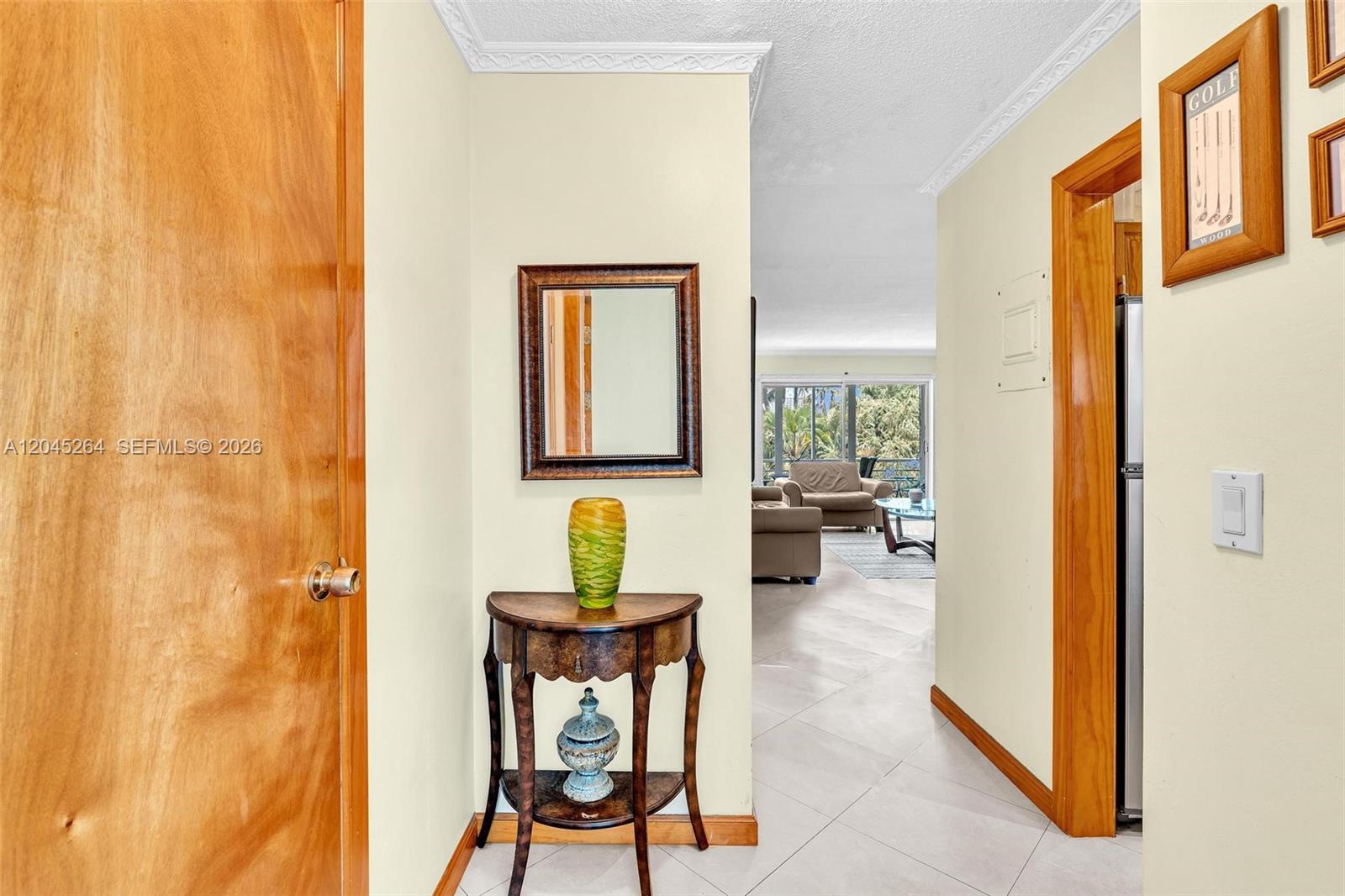 A hallway with a wooden door, a small console table, and a view into a living room — 700 NE 14th Ave # 307, Hallandale Beach FL 33009, HALLANDALE BEACH, FL