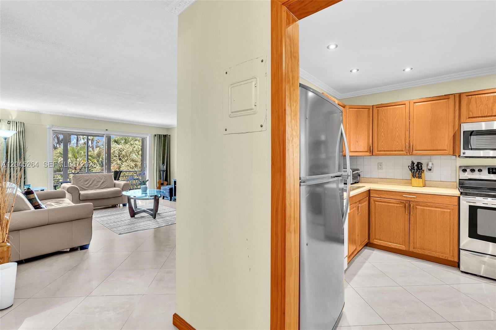 A view from a tiled kitchen into a living room with a sofa and balcony — 700 NE 14th Ave # 307, Hallandale Beach FL 33009, HALLANDALE BEACH, FL