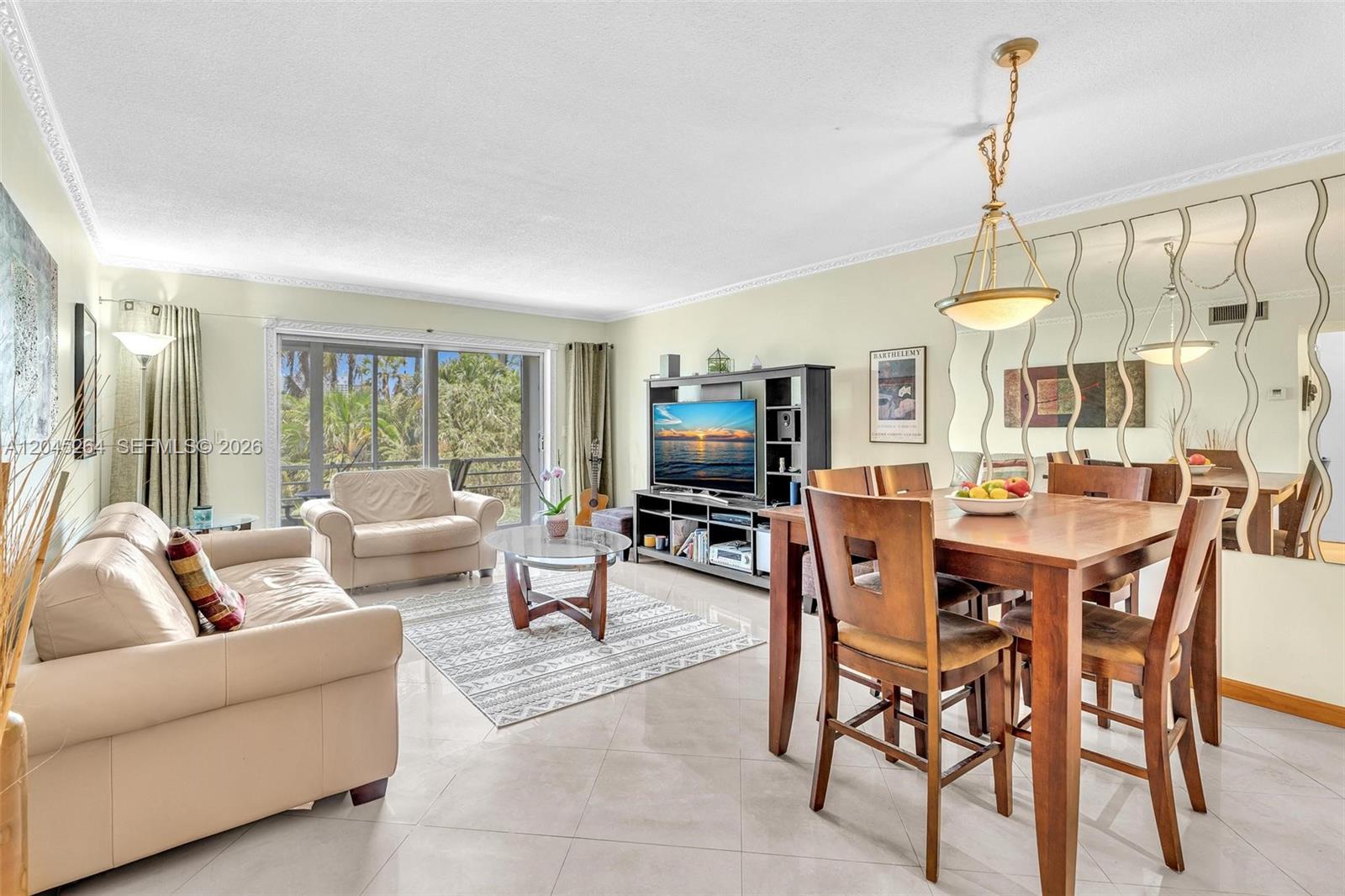 A living and dining room features tile floors, a glass coffee table, and mirrored walls — 700 NE 14th Ave # 307, Hallandale Beach FL 33009, HALLANDALE BEACH, FL