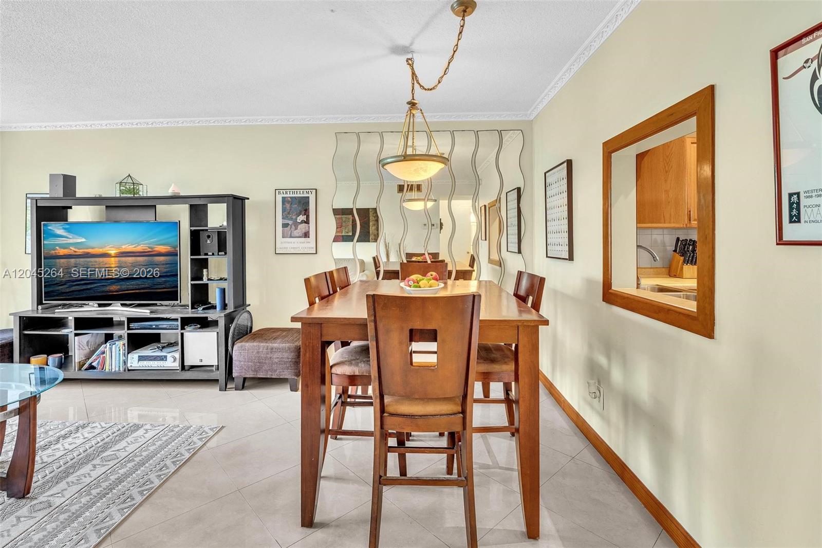 A dining area with a wooden table and chairs sits next to a living room — 700 NE 14th Ave # 307, Hallandale Beach FL 33009, HALLANDALE BEACH, FL