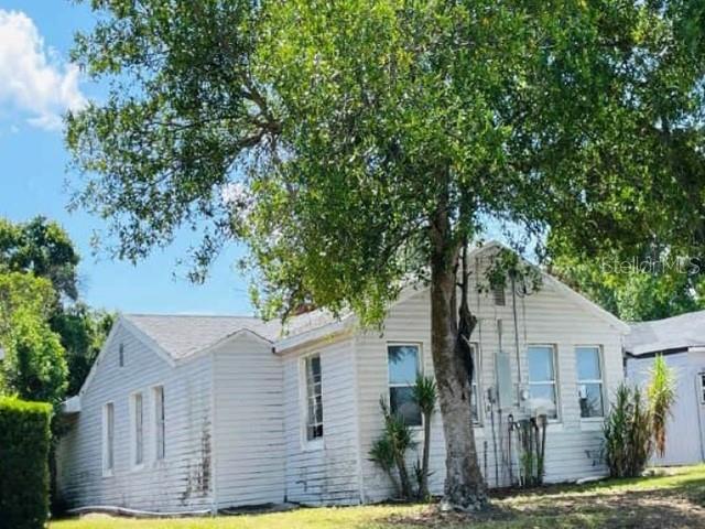 A white, single-story house with horizontal siding is partially shaded by a large tree — 235 MCKEAN STREET, AUBURNDALE, FL