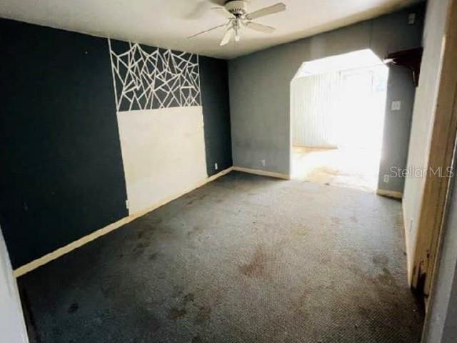 An empty room features dark gray walls, a geometric accent wall, and stained wall-to-wall carpeting — 235 MCKEAN STREET, AUBURNDALE, FL