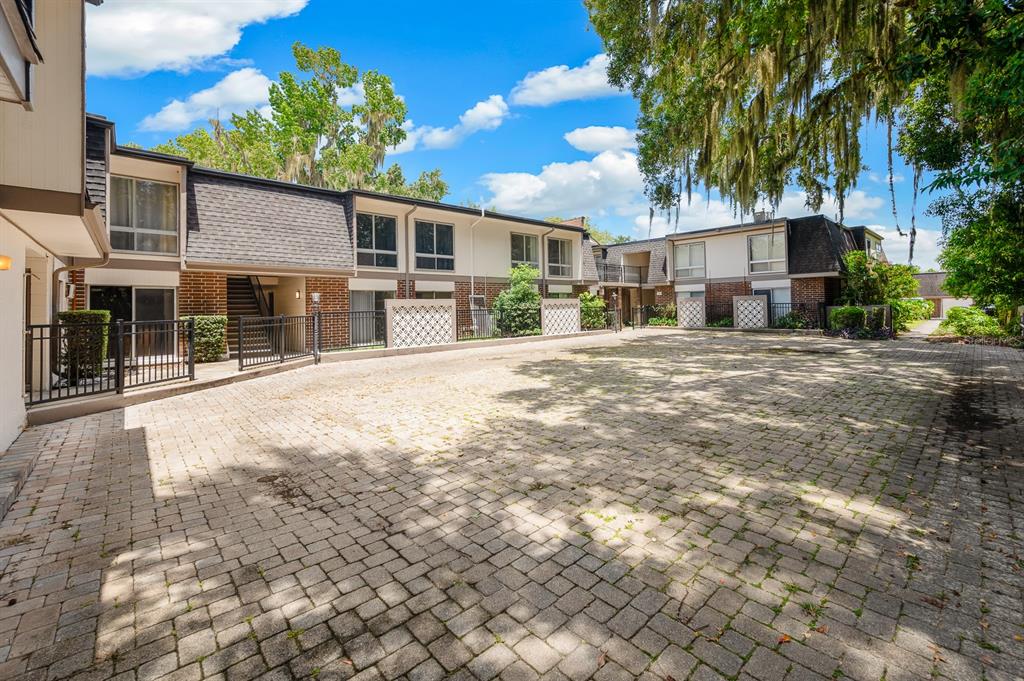 A paved courtyard sits in front of two-story brick and white apartment buildings — 1700 SW 16TH COURT UNIT L26, GAINESVILLE, FL