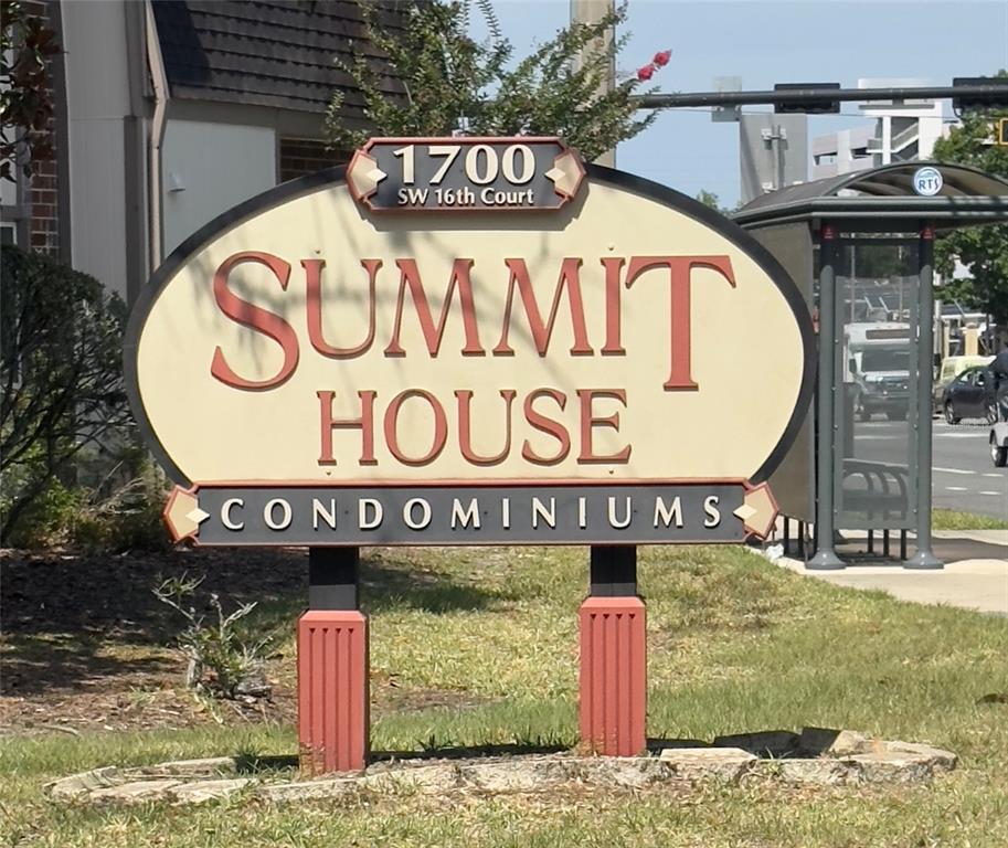 A sign for Summit House Condominiums stands on a grassy lawn near a bus stop — 1700 SW 16TH COURT UNIT L26, GAINESVILLE, FL