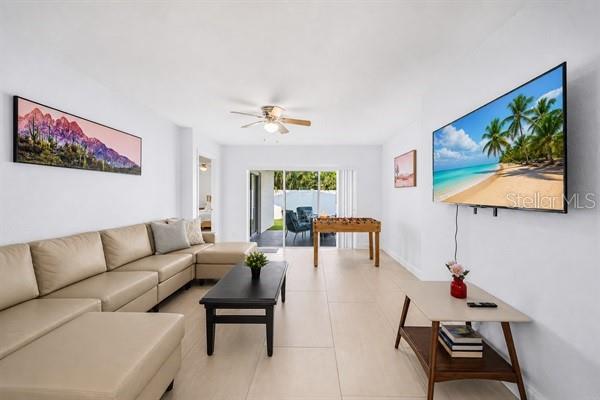 A living room features a beige sectional sofa, a coffee table, and a wall-mounted television — 11355 2ND STREET E, TREASURE ISLAND, FL