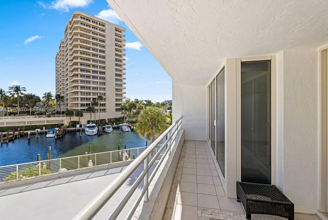 A balcony with tile flooring overlooks a canal with boats and a high-rise building — 4201 N Ocean Blvd # 208, Boca Raton FL 33431, BOCA RATON, FL