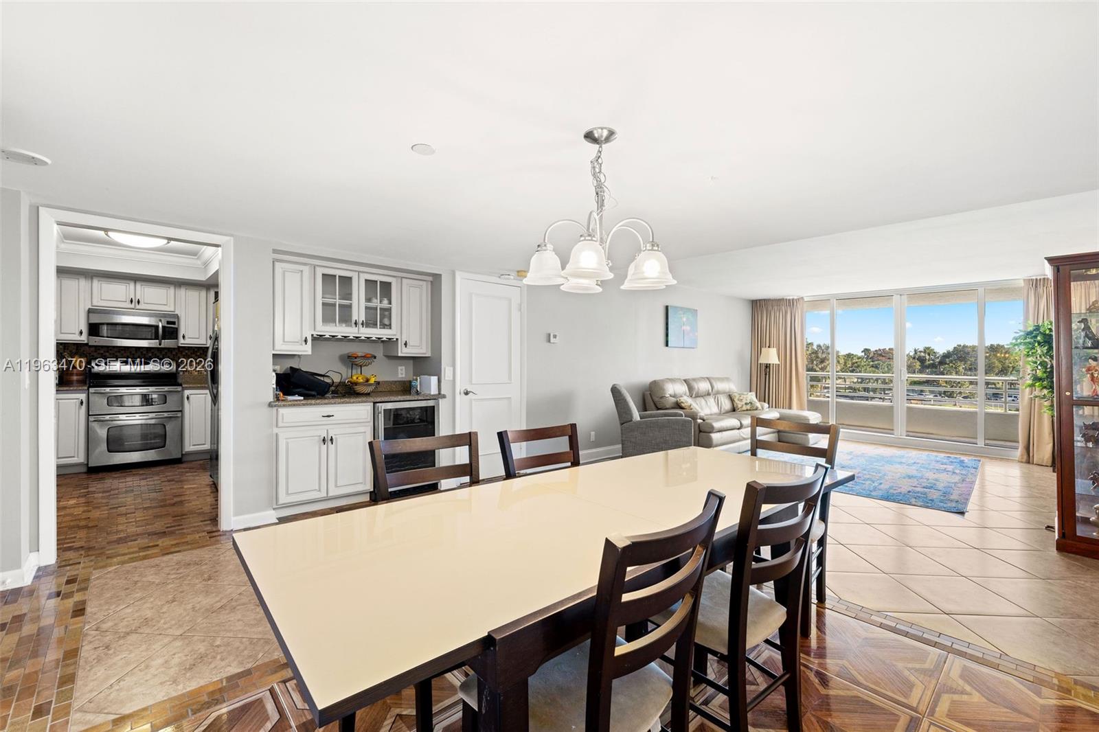 A dining area with a light-colored table and chairs sits adjacent to a kitchen and living room — 4201 N Ocean Blvd # 208, Boca Raton FL 33431, BOCA RATON, FL