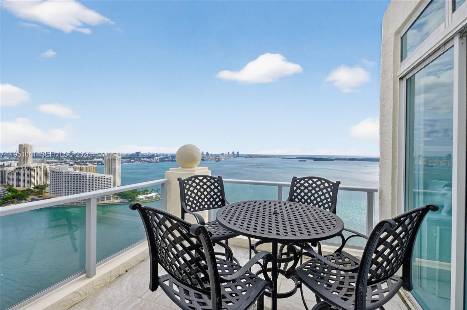 A balcony with a black metal dining set overlooks a bay and city skyline — 1155 Brickell Bay Dr, Miami FL 33131, MIAMI, FL